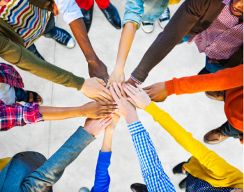 The benefits of tithing can include improving relationships and creating new relationships.  Here, people put their hands in a circle.