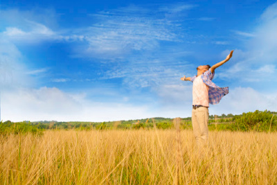 Man rejoicing in a field with arms outstretched.  This is the experience you can have after doing a forgiveness prayer and releasing resentments.