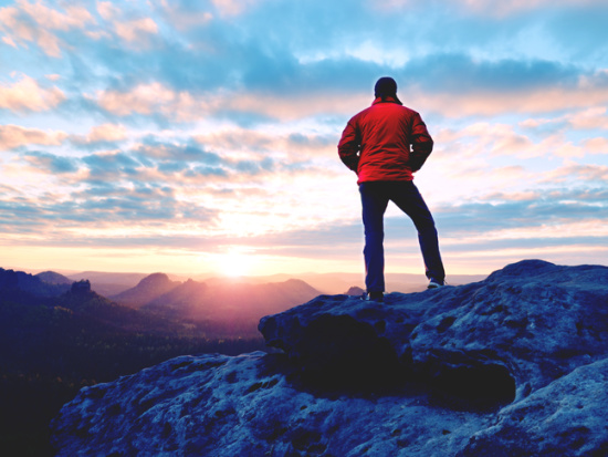 Man on mountain looking at the sunrise representing the sacral chakra element of personal power